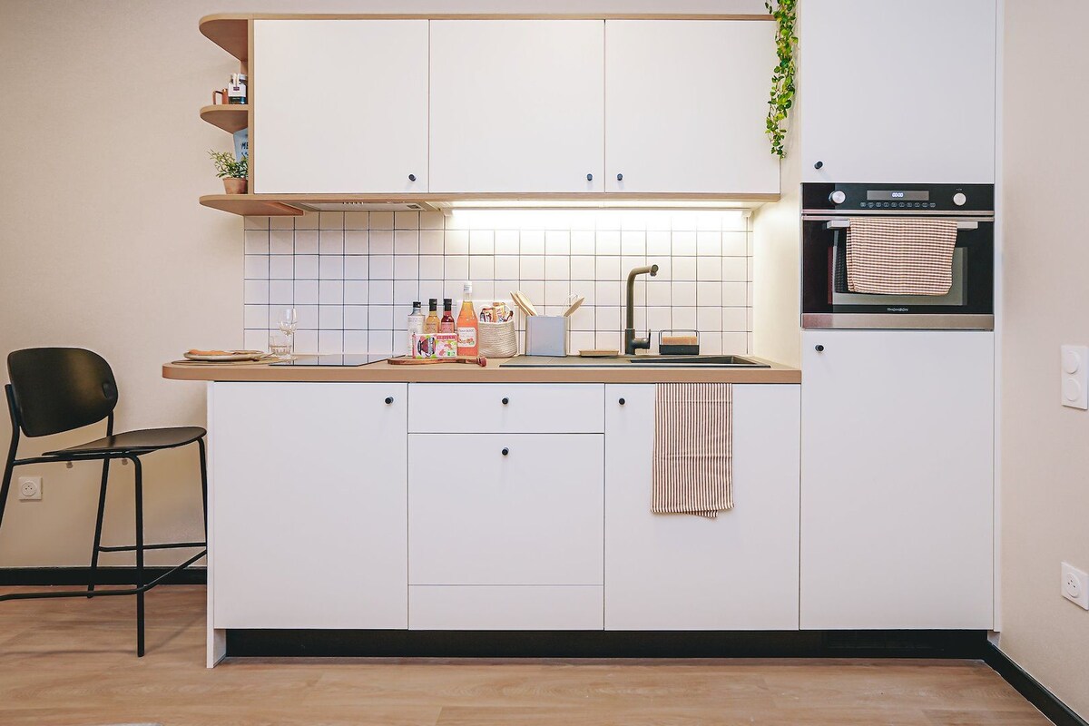 A compact kitchen with white cabinets, a built-in oven, and a small countertop.