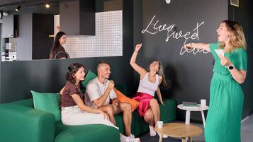 Un intérieur moderne avec un canapé vert, une petite table ronde et un panneau néon sur lequel on peut lire : « Vivez pleinement ».