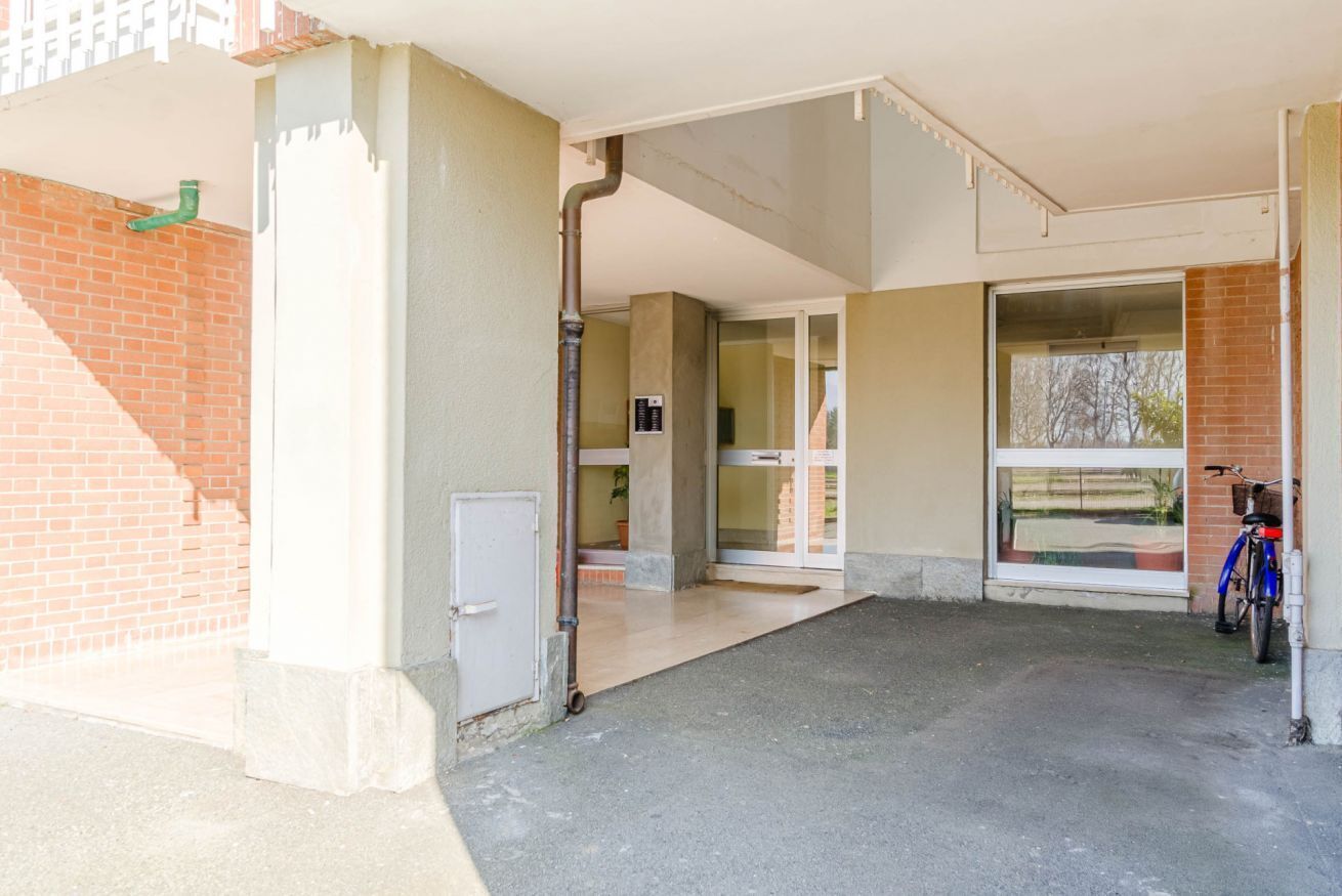 A building entrance with a concrete ramp, a glass door, and a bicycle parked outside.