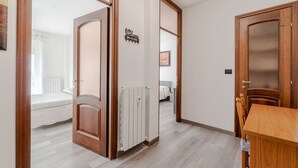 Ein Flur mit Holztür, Heizkörper und einem Bett im Hintergrund.