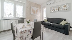 Ein Zimmer mit einem Esstisch, Stühlen, einer Couch und einer Wand mit einem floralen Gemälde.