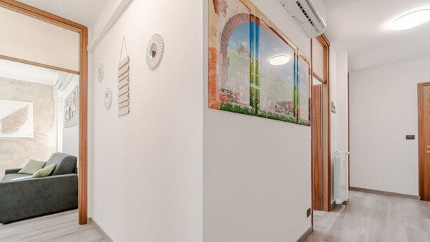 Ein Flur mit einem grauen Sofa, einer Wand mit einem gerahmten Bild und einer Tür mit einem Handtuchhalter.