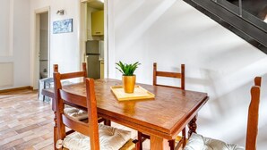 Un comedor con mesa de madera, sillas, una planta en maceta y una escalera.