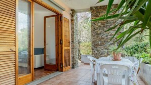 Un patio con tavolo e sedie, una porta in legno e un muro in pietra.