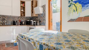 Una cucina con mobili bianchi, un forno a microonde, una macchina da caffè e uno schienale piastrellato.