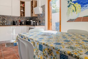A kitchen with white cabinets, a microwave, a coffee maker, and a tiled backsplash.