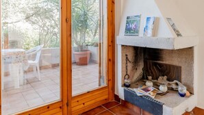 Una stanza con camino, un'area pranzo con tavolo e sedie, e vista sull'esterno.