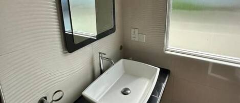 A bathroom with a white sink, a mirror, and a window with blinds.