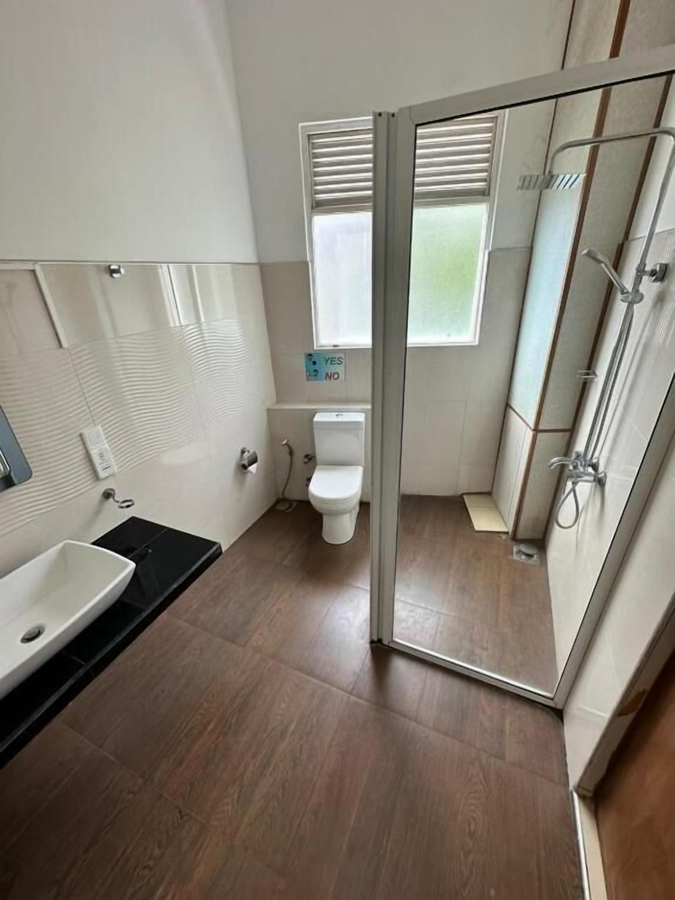 A modern bathroom with a glass shower enclosure, a white toilet, and a sink.
