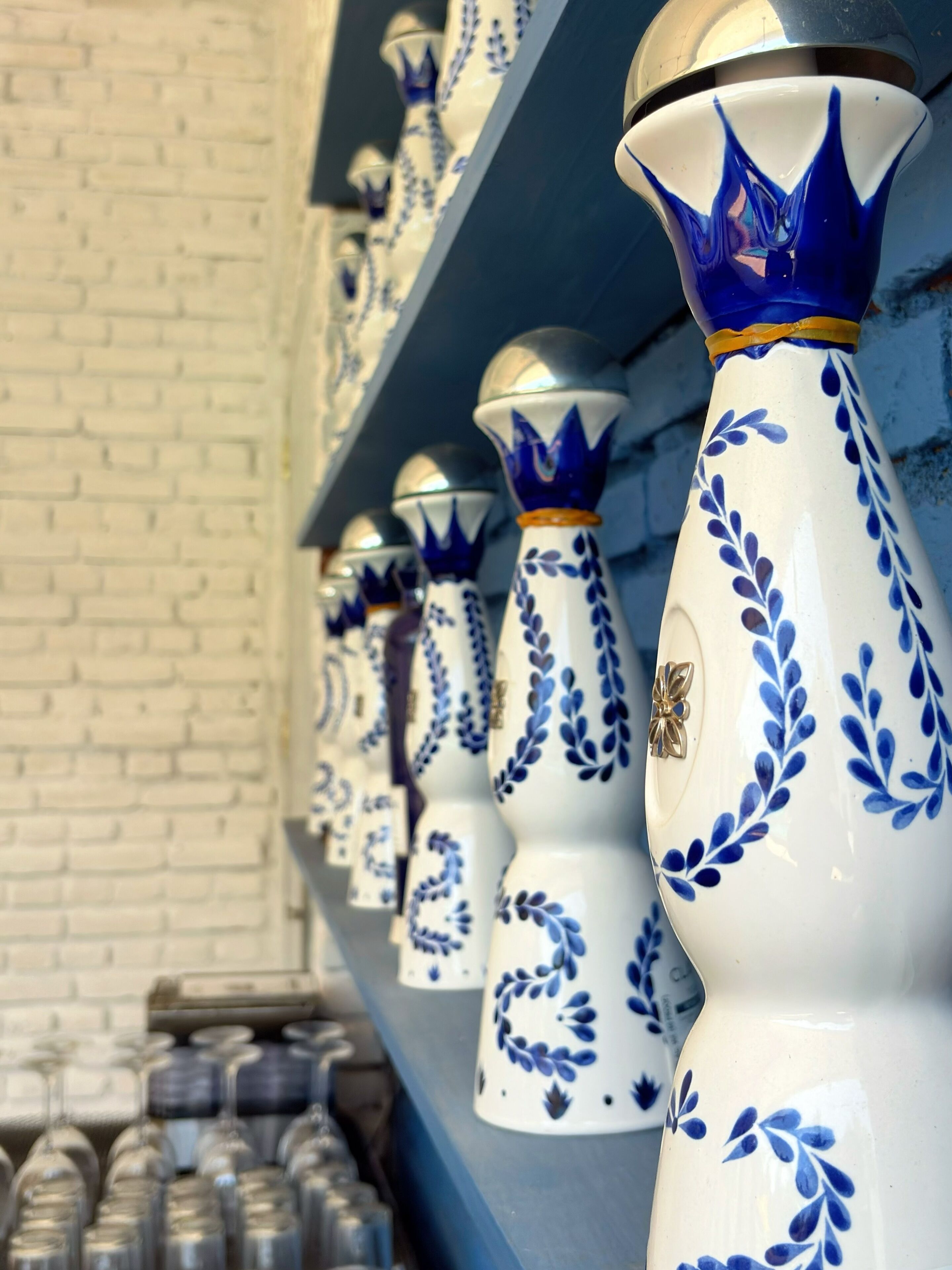 A row of white vases with blue floral patterns and gold accents on a shelf.