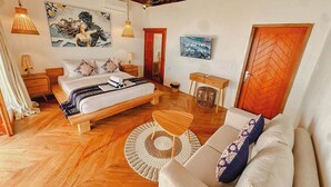 A spacious bedroom with a large bed, wooden floor, and a ceiling with exposed beams. - RATU Village – Luxury Island Apartment & Private Villa Gili Air (Gili Air)