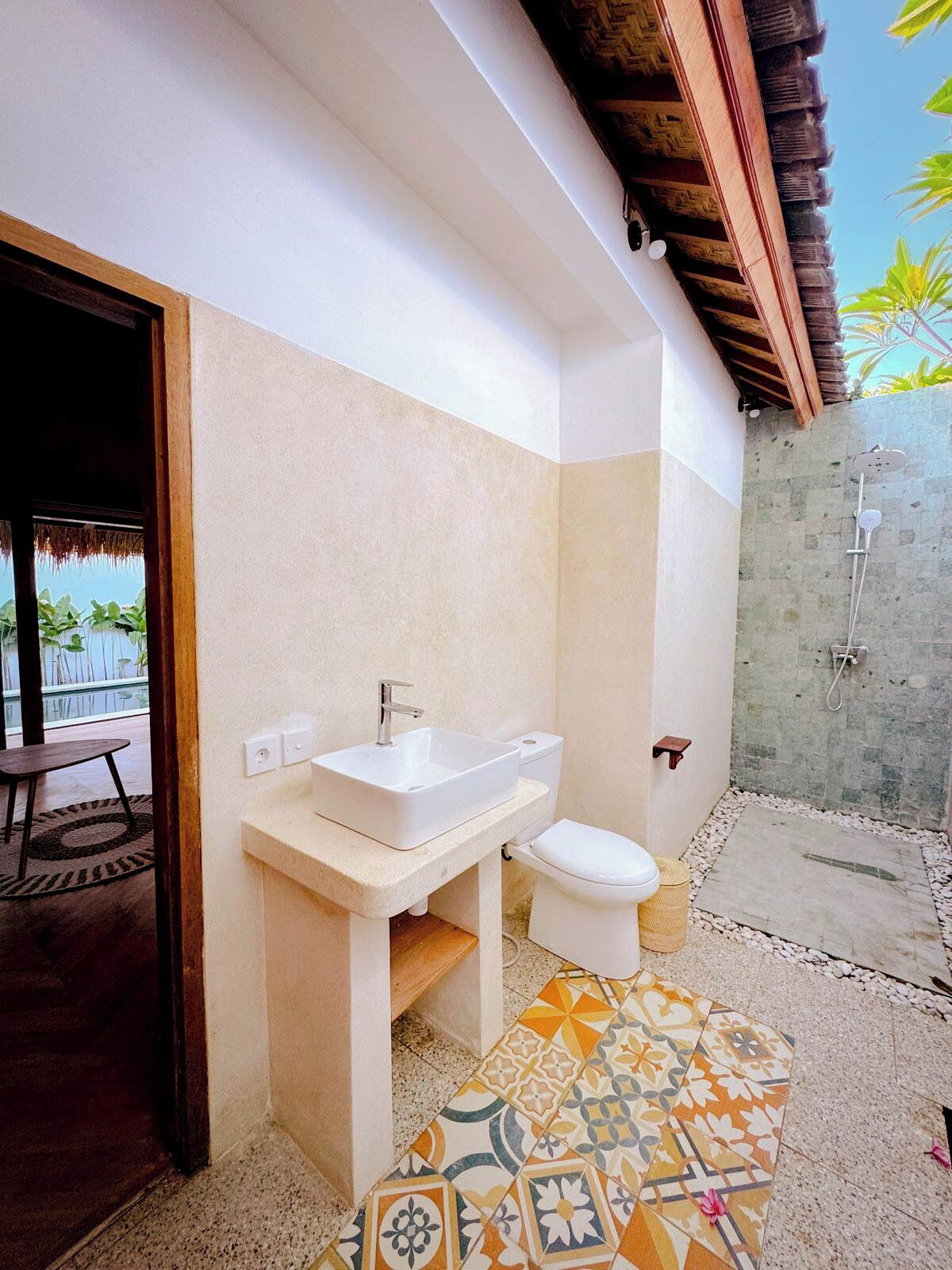 Une salle de bain avec un lavabo, des toilettes et une douche, le tout de couleur blanche.