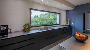 A modern kitchen with a large window, dark cabinetry, and a fruit bowl on the counter.