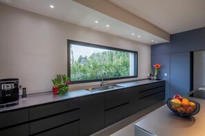 Enjoy a serene atmosphere in this kitchen with a large window overlooking lush greenery, a coffee maker, and a microwave.