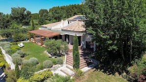 A house with a covered patio, a garden with various plants, and a view of the surrounding greenery.