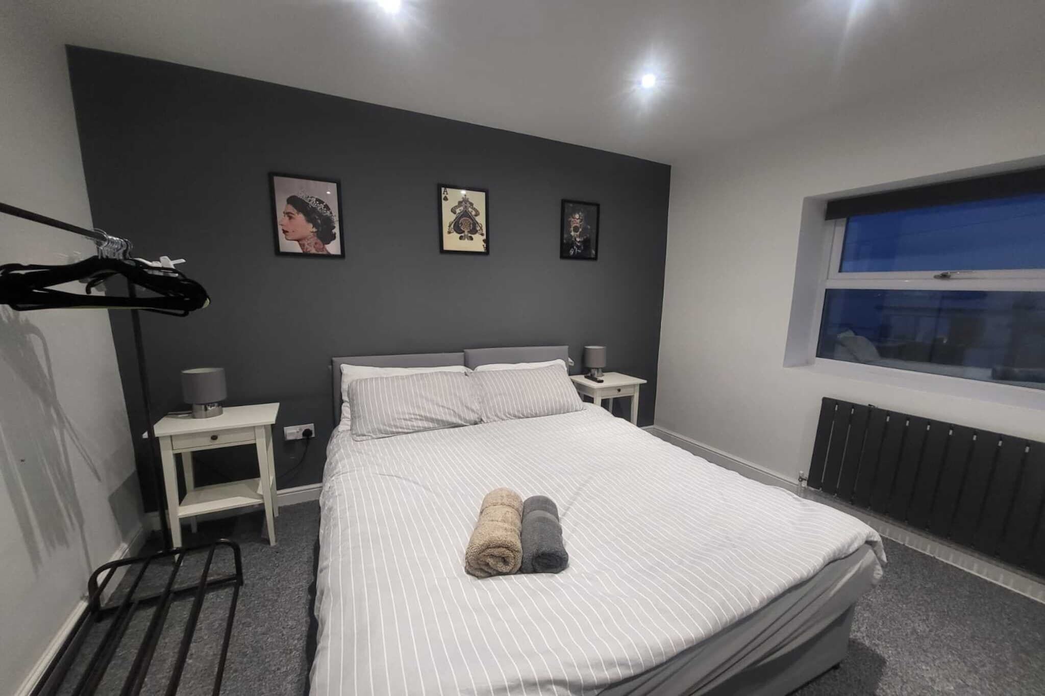 Una cama bien hecha con dos toallas, una mesita de noche con lámpara, y una ventana con vistas.