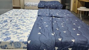 Ein Schlafzimmer mit einem großen Bett, einem Kleiderschrank, einem Schreibtisch und einem durch eine offene Tür einsehbaren Badezimmer.