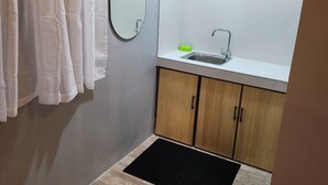 Ein kleines Badezimmer mit Holzschrank, Waschbecken und Spiegel.