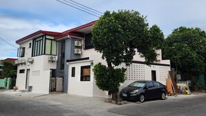 Ein modernes, zweistöckiges Haus mit rotem Dach, Klimaanlagen und einem parkenden Auto.