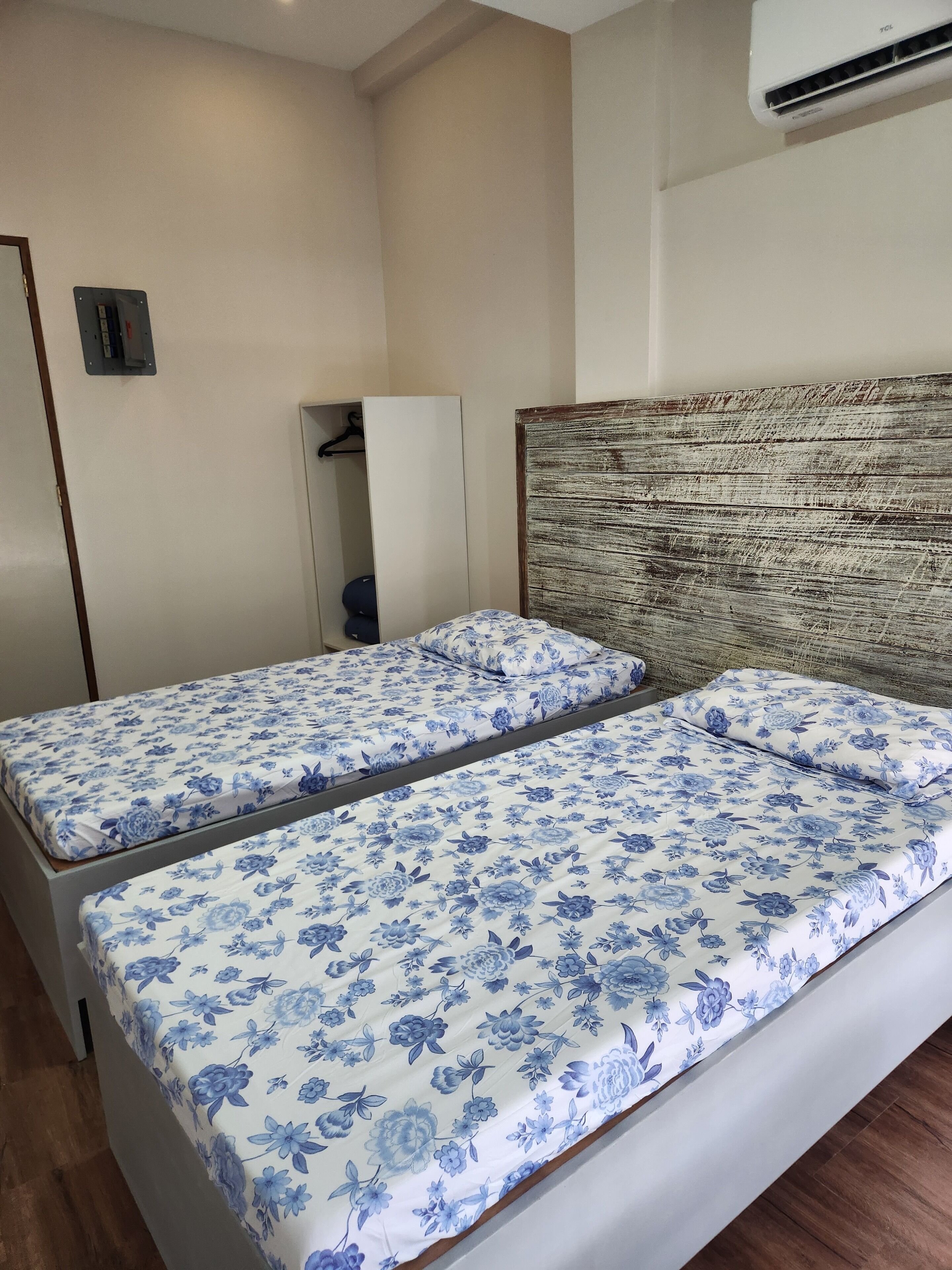 Une chambre avec deux lits simples, une armoire et un appareil de climatisation.