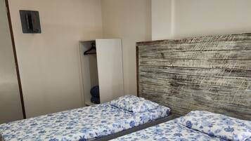 Une chambre avec deux lits simples, une armoire et un appareil de climatisation.