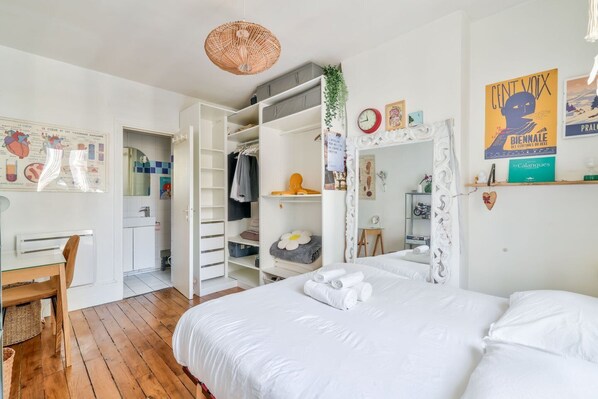 A bedroom with a large bed, a desk, a wardrobe, and a mirror.
