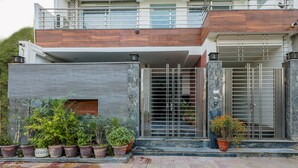 A modern two-story house with a balcony, a gated entrance, and potted plants. - Mauryan Signature hotel with Airport View (New Delhi)
