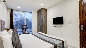 A bedroom with a bed, a television on the wall, a window, and a door. - Mauryan Signature hotel with Airport View (New Delhi)