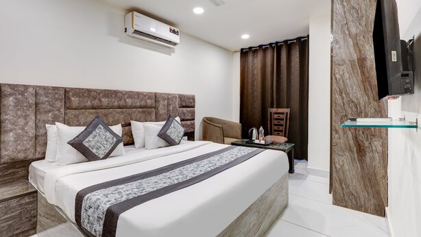 A modern hotel room with a large bed, a flat-screen TV, a desk, and a chair. - Mauryan Signature hotel with Airport View (New Delhi)