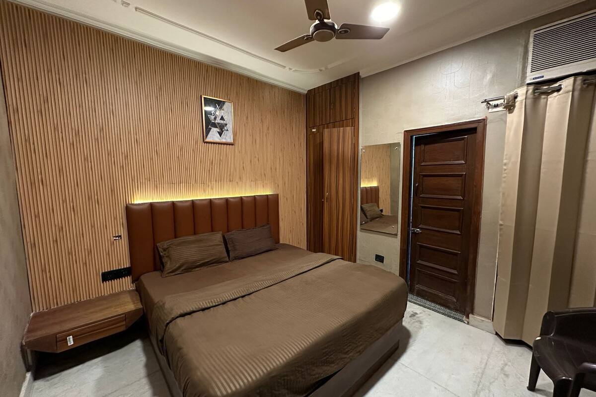 A bedroom with a bed, a wooden headboard, a ceiling fan, a wardrobe, and a mirror.