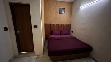 Une chambre à coucher avec un lit, un ventilateur de plafond, une porte en bois et un luminaire fixé au mur.