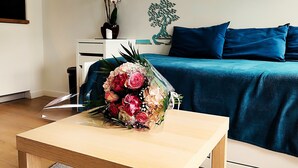 Ein Zimmer mit einem Bett, einem Schreibtisch und einem Blumenstrauß auf dem Schreibtisch.
