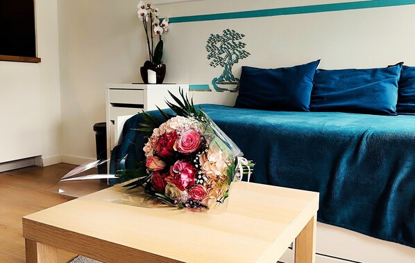 Una habitación con una cama, un escritorio y un ramo de flores sobre el escritorio.