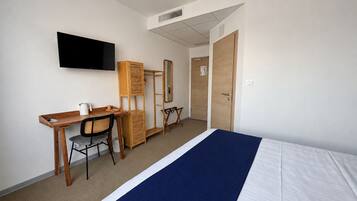 A hotel room with a bed, a desk, a chair, a television, and a wardrobe.