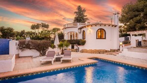 A white villa with a swimming pool, surrounded by trees and a sunset sky. - Casa Golondrina (Moraira)