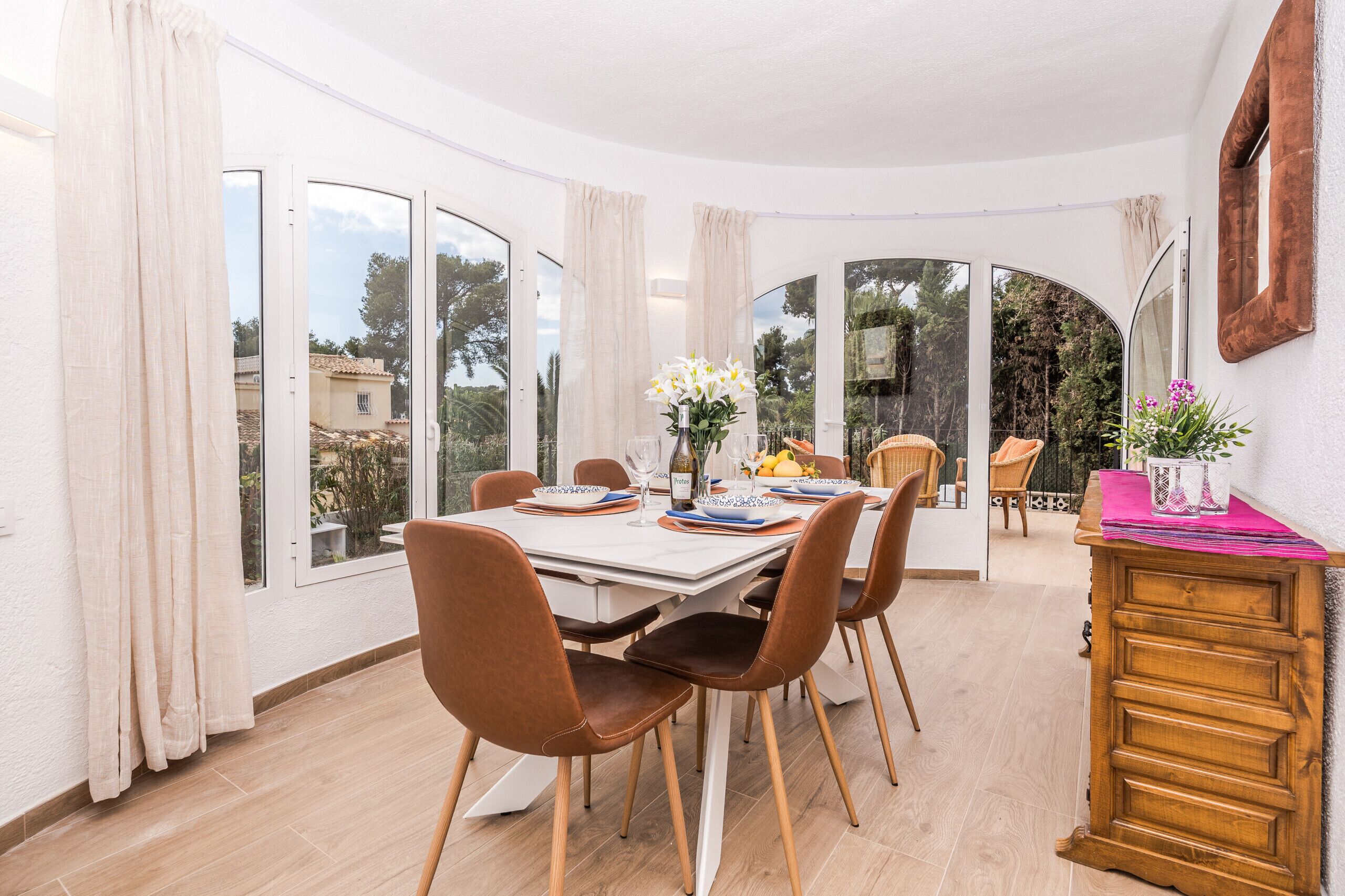 A dining area with a table set for four, large windows, and a view of the outdoors.