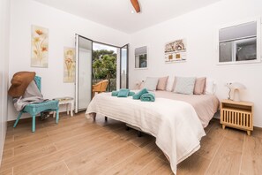 A bedroom with a bed, a chair, a nightstand, and a window.