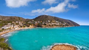 A coastal town with buildings on a hillside overlooking turquoise waters. - Casa Golondrina (Moraira)
