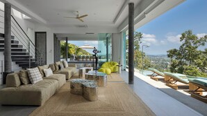 A modern living room with a sofa, coffee table, and a view of a balcony with outdoor seating.