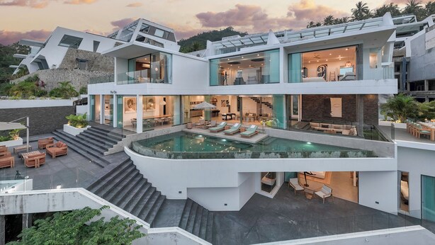 A modern multi-story house with a central pool, outdoor seating, and a staircase leading to the upper levels.