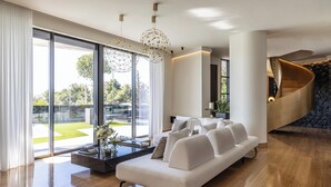 A modern living room with a white sofa, a coffee table, and a large window offering a view of the outdoors.