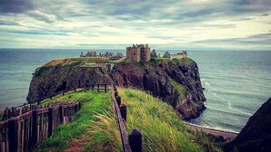 A coastal castle on a cliff overlooking the sea.