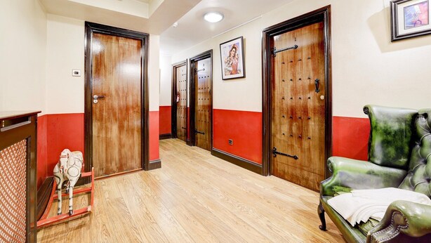 A hotel corridor with wooden doors, a green leather sofa, and a small decorative horse statue.