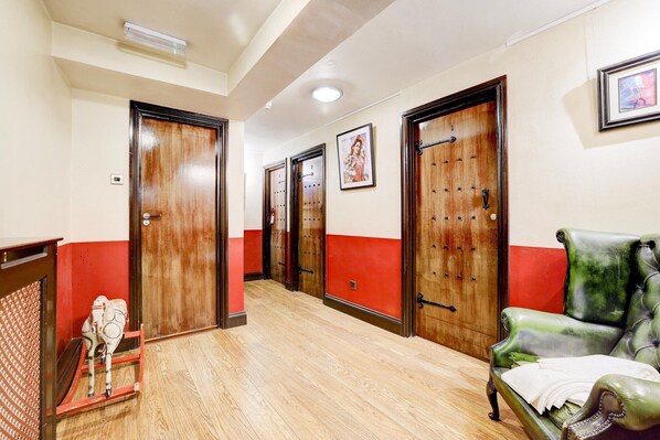 A hotel corridor with wooden doors, a green leather sofa, and a small decorative horse statue.