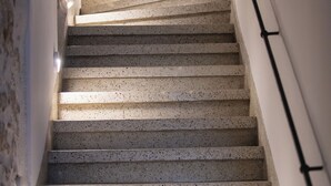 A staircase with speckled steps, a handrail on the right, and a light fixture at the top.