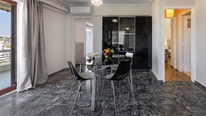 A modern dining area with a glass table, black chairs, and a fruit bowl. - Seaside Secret Sea View Two Bedroom Apartment by BluPine (Athens)