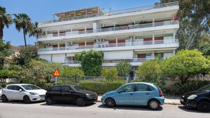 A multi-story building with balconies, parked cars, and a triangular warning sign. - Seaside Secret Sea View Two Bedroom Apartment by BluPine (Athens)