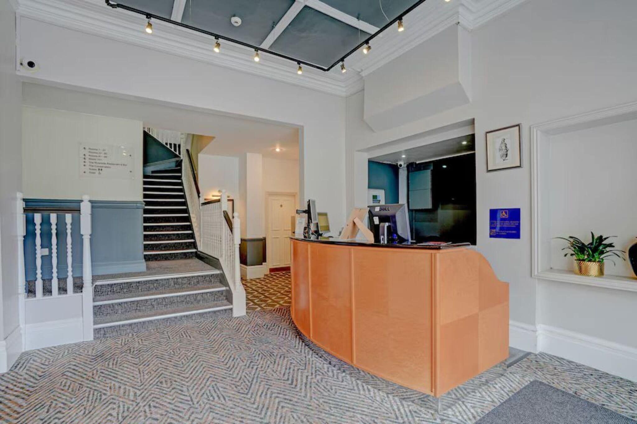 A reception area with a desk, a staircase, and a wall-mounted sign.