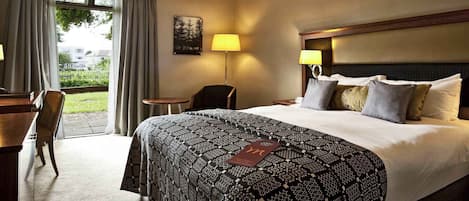 A hotel room with a large bed, two bedside lamps, a desk, and a chair.