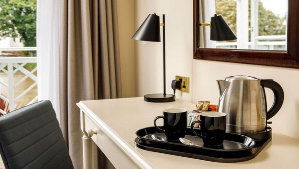 Ein Hotelzimmer mit Schreibtisch, Wasserkocher, zwei Tassen und Tablett.